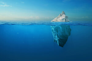 Iceberg en el océano mostrando la pequeña parte visible sobre la superficie y la gran masa oculta bajo el agua, metáfora de la diferencia entre visibilidad e influencia.