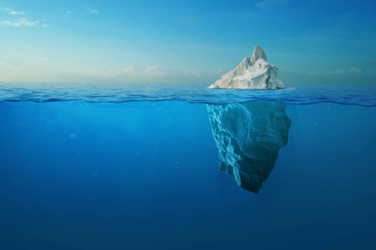 An iceberg in the ocean showing the small visible portion above the surface and the vast hidden mass beneath, a metaphor for the difference between visibility and influence.