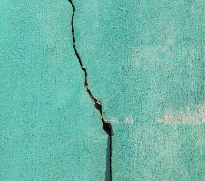 Grieta vertical en una pared turquesa que representa cómo una crisis revela las debilidades estructurales previas del sistema de comunicación de una organización.
