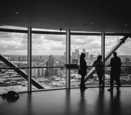 Tres directivos observando la ciudad desde una sala de reuniones de altura