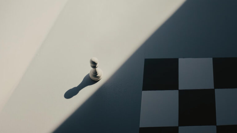 A chess piece off the board, partially lit, with the board in the background in shadow