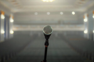 Micrófono en primer plano con sala vacía al fondo, imagen que representa la diferencia entre visibilidad y legitimidad en la comunicación con medios.
