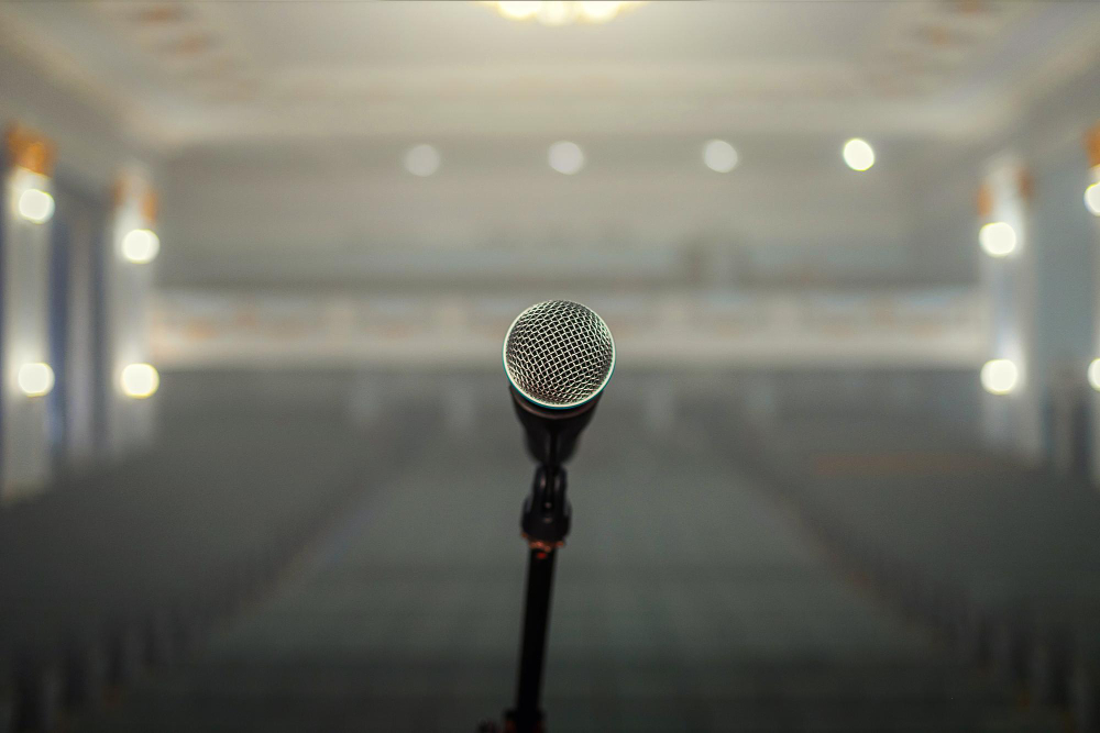 Micrófono en primer plano con sala vacía al fondo, imagen que representa la diferencia entre visibilidad y legitimidad en la comunicación con medios.