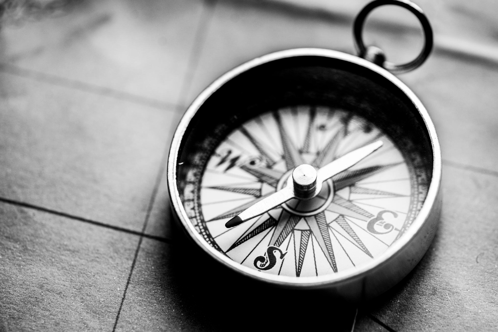 Vintage analogue compass in black and white on a stone surface, a symbol of judgement as orientation in an environment of speed and uncertainty.
